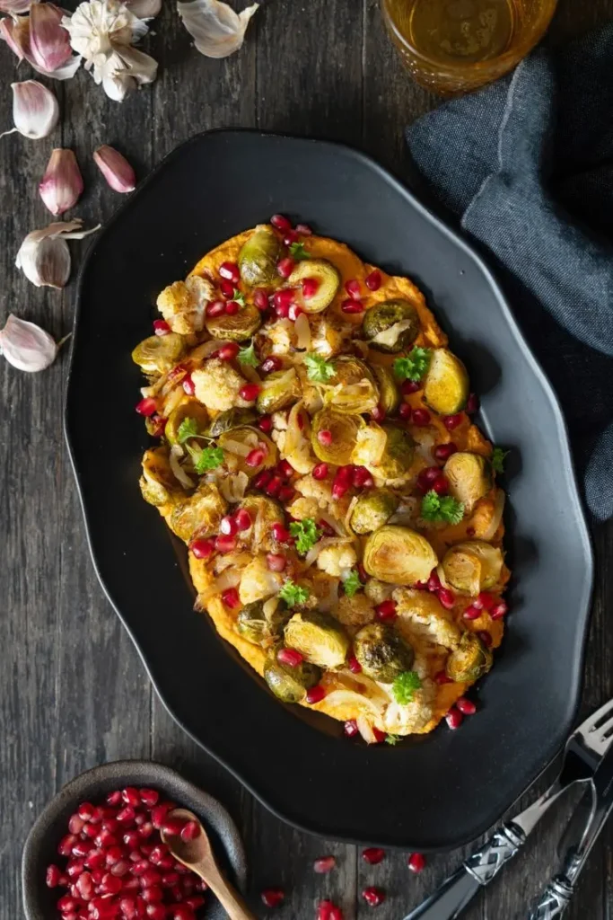 Oven-roasted Brussels sprouts on hummus, topped with pomegranate seeds